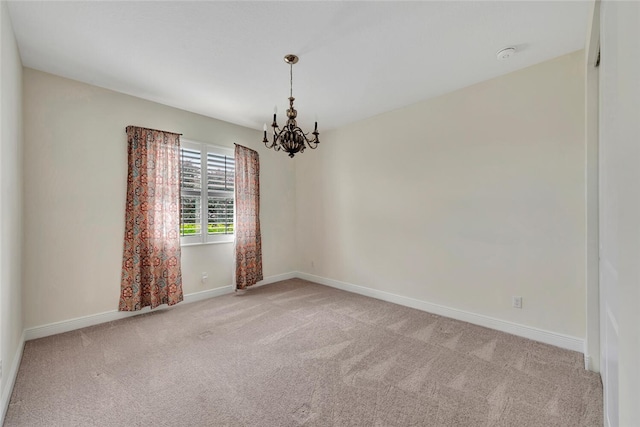 carpeted empty room with a notable chandelier