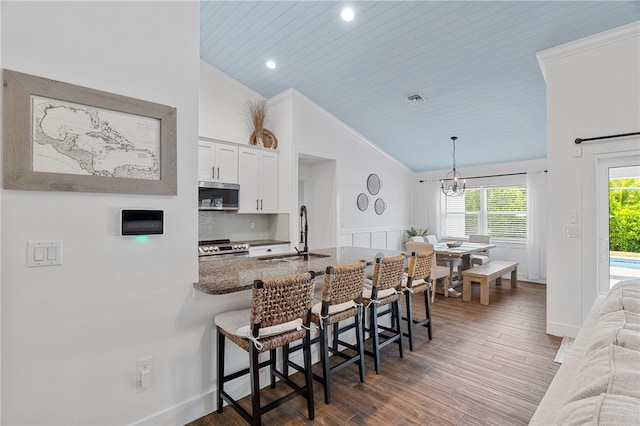 1368 Scroll St, Sebastian, FL 32958 - kitchen with vaulted ceiling, stainless steel appliances, a breakfast bar, white cabinetry, and a chandelier