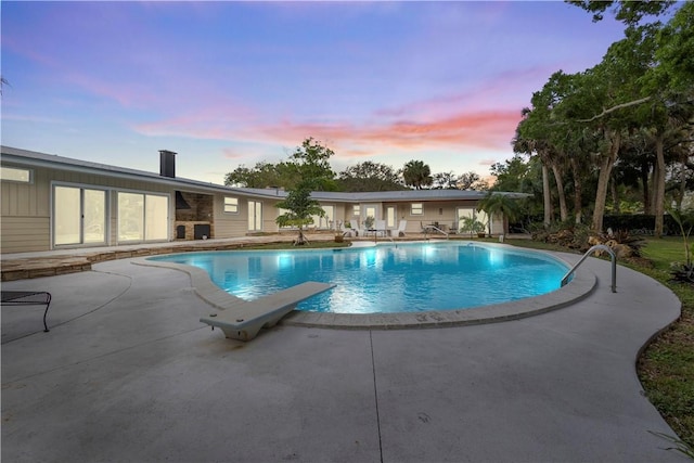 pool at dusk featuring a patio area and an outdoor pool