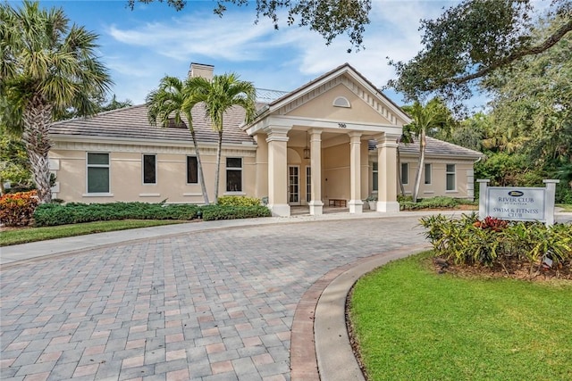 1624 Weybridge Cir, Vero Beach, FL 32963 - view of front of house with stucco siding, a chimney, a front lawn, and curved driveway