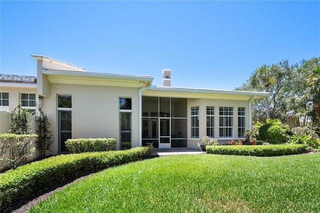 1624 Weybridge Cir, Vero Beach, FL 32963 - rear view of house featuring stucco siding, a sunroom, and a lawn
