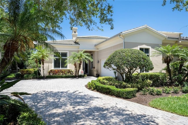 1624 Weybridge Cir, Vero Beach, FL 32963 - view of front of property with decorative driveway, stucco siding, a chimney, and an attached garage