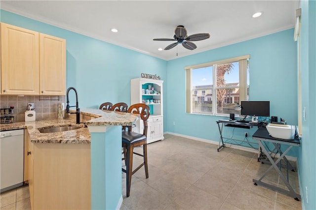 kitchen featuring sink, a kitchen breakfast bar, decorative backsplash, white dishwasher, and light stone counters