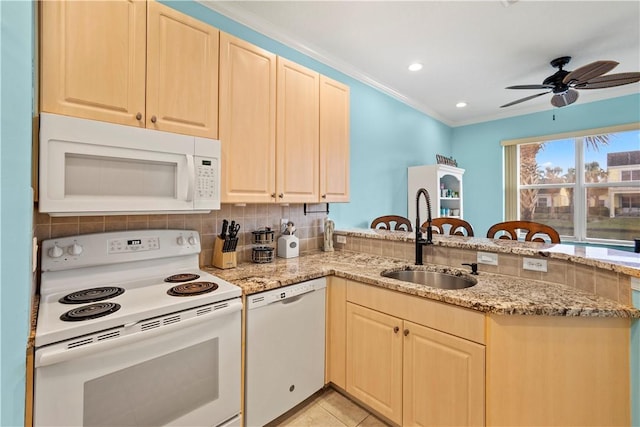 kitchen with light stone counters, white appliances, kitchen peninsula, and sink