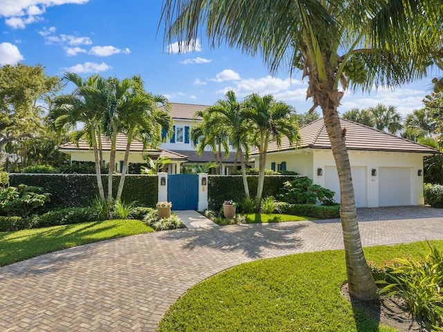 view of front of house featuring a gate, an attached garage, stucco siding, a fenced front yard, and decorative driveway