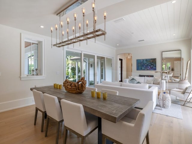 dining space with recessed lighting, arched walkways, light wood-style flooring, and ornamental molding