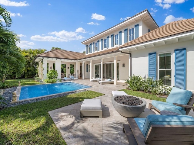 rear view of house featuring stucco siding, an outdoor hangout area, a tile roof, and a patio