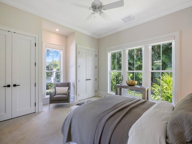 bedroom with crown molding, baseboards, multiple closets, ceiling fan, and light colored carpet