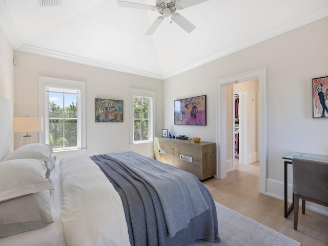 bedroom with lofted ceiling, a spacious closet, multiple windows, and light wood-style flooring