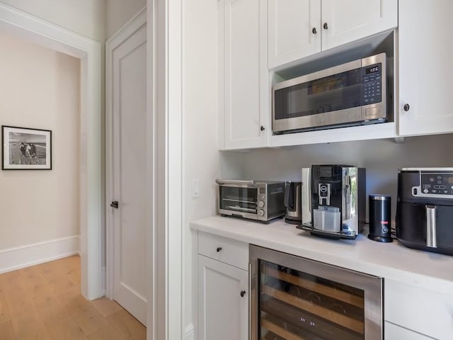 bar featuring stainless steel microwave, baseboards, wine cooler, a toaster, and light wood-style floors