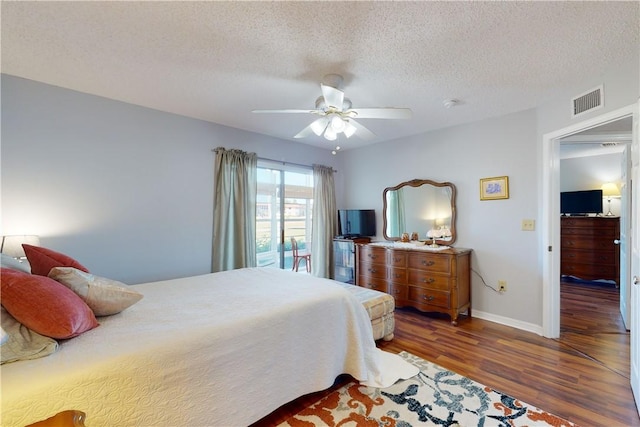 bedroom with dark hardwood / wood-style flooring, ceiling fan, and a textured ceiling