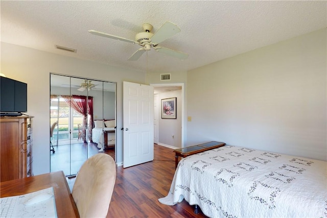 bedroom with ceiling fan, dark hardwood / wood-style floors, a textured ceiling, and a closet