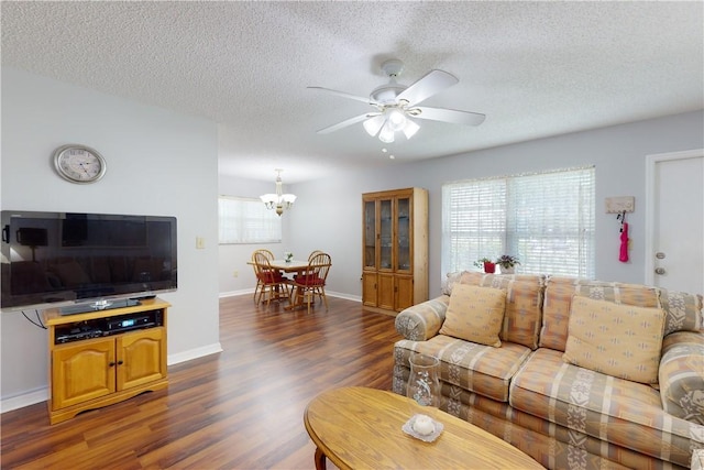 living room with dark hardwood / wood-style flooring, ceiling fan with notable chandelier, and a textured ceiling