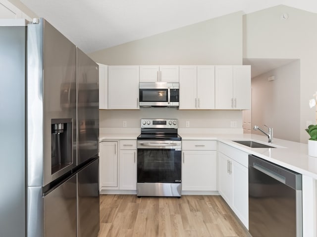 kitchen featuring stainless steel appliances, white cabinetry, sink, vaulted ceiling, and light hardwood / wood-style floors