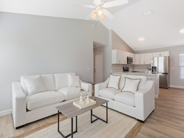 living room with high vaulted ceiling, ceiling fan, and light hardwood / wood-style floors