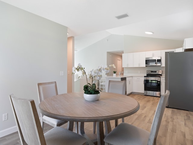 dining room featuring vaulted ceiling and light hardwood / wood-style floors