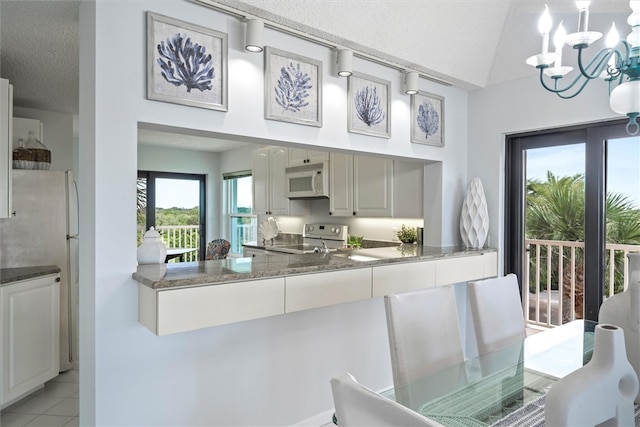 8830 S Sea Oaks Way Unit 301, Vero Beach, FL 32963 - kitchen featuring white appliances, a chandelier, vaulted ceiling, and light tile patterned flooring