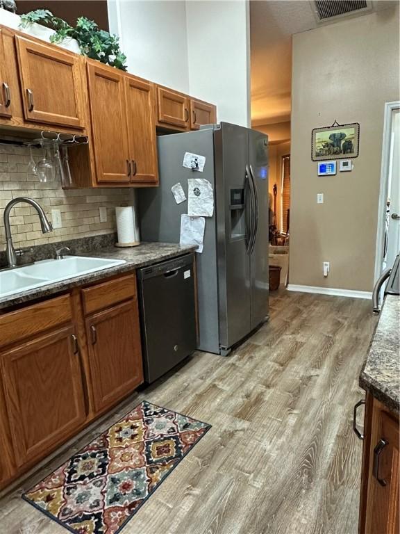 kitchen featuring light hardwood / wood-style flooring, sink, backsplash, stainless steel fridge with ice dispenser, and black dishwasher