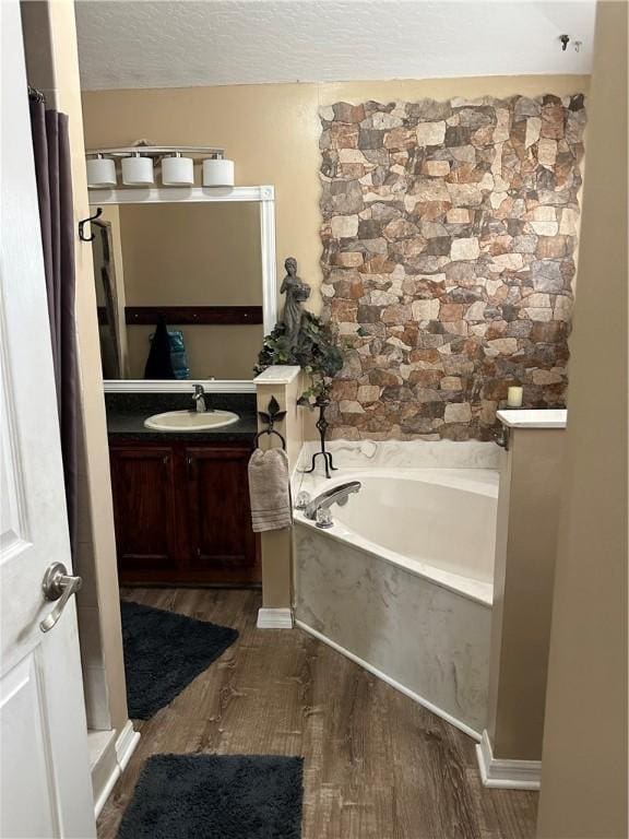 bathroom with vanity, a washtub, a textured ceiling, and wood-type flooring