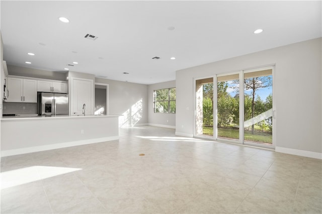 unfurnished living room with sink and light tile patterned floors