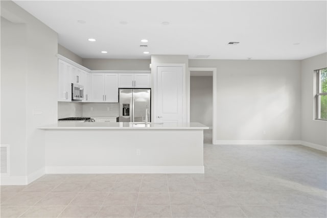 kitchen with white cabinetry, sink, stainless steel appliances, kitchen peninsula, and light tile patterned floors