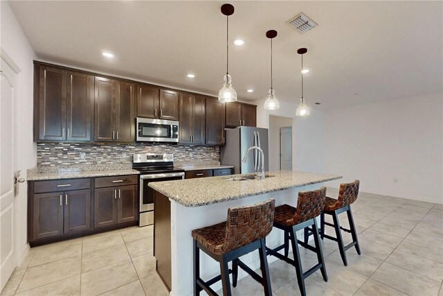 9036 103rd Ave, Vero Beach, FL 32967 - kitchen featuring stainless steel appliances, decorative backsplash, dark brown cabinetry, a kitchen breakfast bar, and recessed lighting