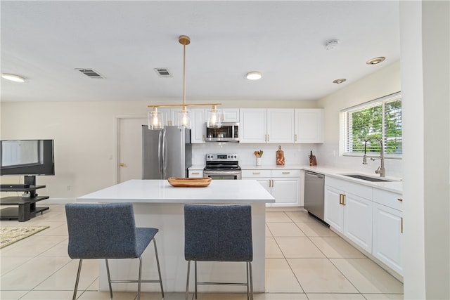 kitchen with white cabinetry, sink, a center island, hanging light fixtures, and stainless steel appliances