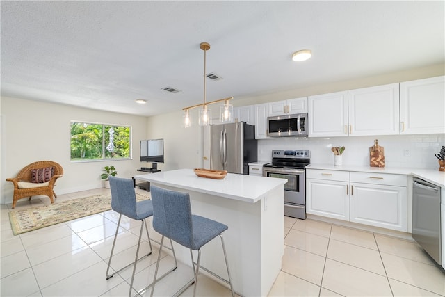 kitchen featuring a breakfast bar area, backsplash, white cabinetry, and stainless steel appliances