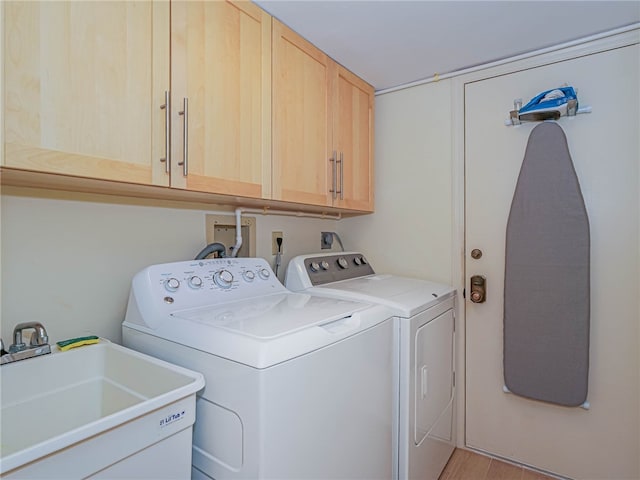 laundry room featuring light hardwood / wood-style floors, cabinets, sink, and separate washer and dryer