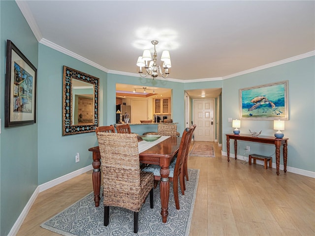 dining space with light hardwood / wood-style flooring, crown molding, and an inviting chandelier