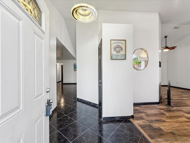 hall featuring baseboards, marble finish floors, and a towering ceiling