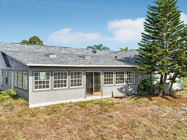 back of property featuring a shingled roof and a lawn