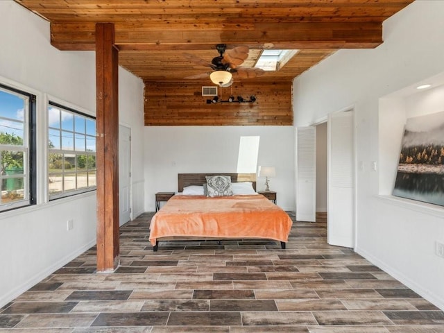 bedroom with wooden ceiling, a towering ceiling, wood finished floors, baseboards, and beam ceiling
