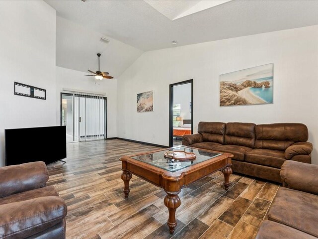 living room with wood finished floors, ceiling fan, high vaulted ceiling, and baseboards