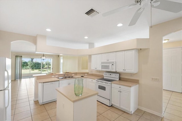 413 W Tangerine Sq SW, Vero Beach, FL 32968 - kitchen with white appliances, arched walkways, a peninsula, light tile patterned floors, and white cabinetry