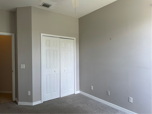 unfurnished bedroom with a closet, a textured ceiling, ceiling fan, and carpet floors