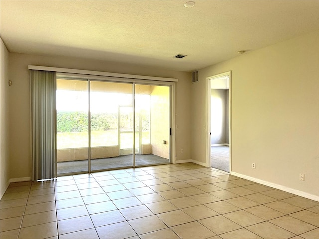 tiled empty room with a textured ceiling