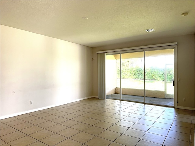 tiled spare room with a textured ceiling