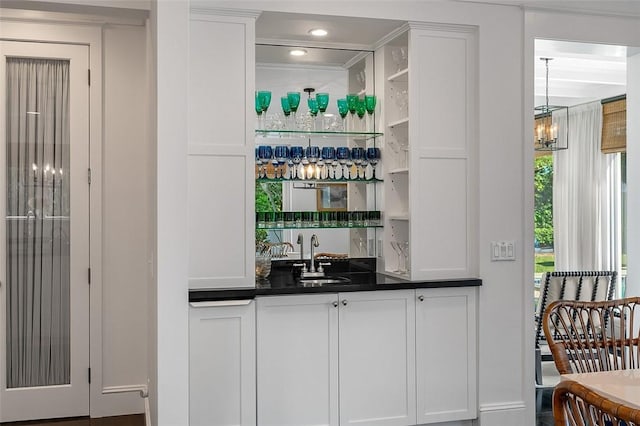 bar featuring white cabinetry, sink, and a chandelier