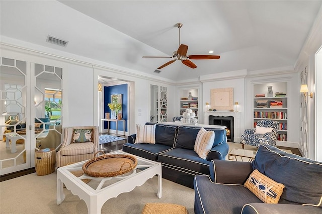 carpeted living room with french doors, ceiling fan, a raised ceiling, and built in features