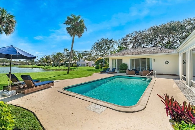 view of swimming pool with a water view, a patio area, and a lawn