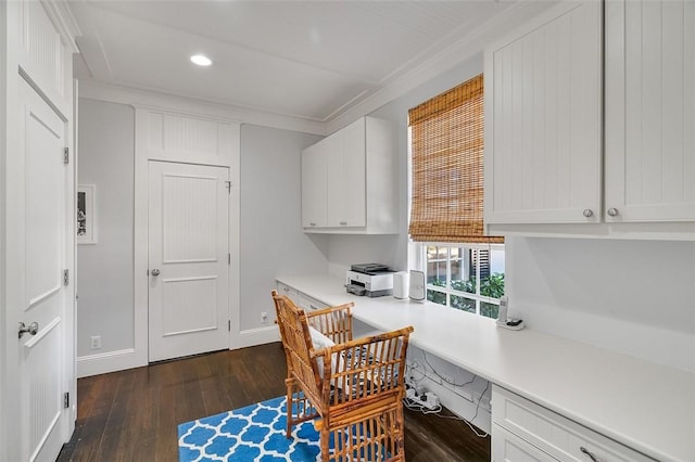 home office with dark wood-type flooring, crown molding, and built in desk