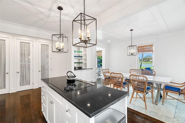 kitchen with pendant lighting, crown molding, white cabinets, a kitchen island, and black electric cooktop