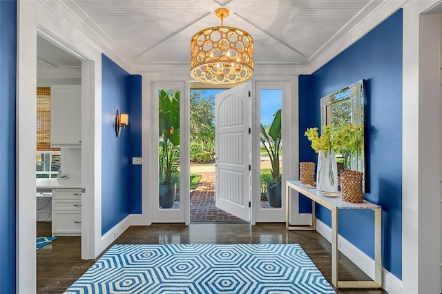 doorway with crown molding, dark hardwood / wood-style flooring, and an inviting chandelier