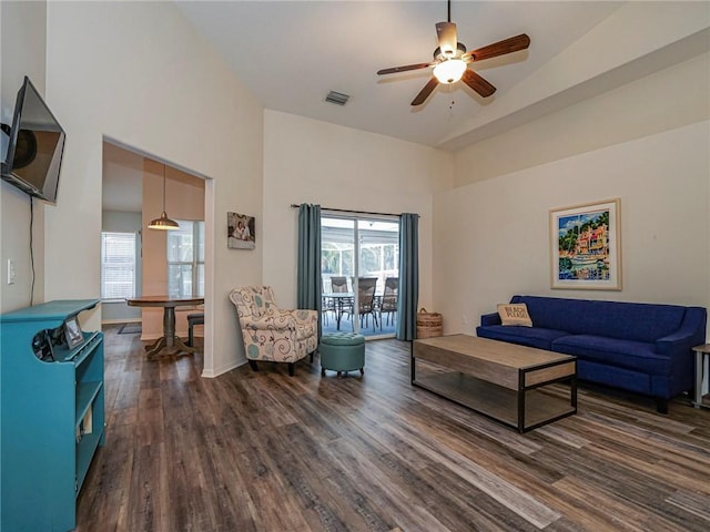 living room with ceiling fan, dark hardwood / wood-style flooring, and a high ceiling