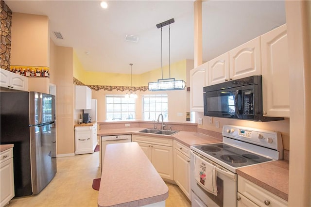 1018 Persian Ln, Sebastian, FL 32958 - kitchen featuring white range with electric cooktop, black microwave, freestanding refrigerator, a peninsula, and white cabinets