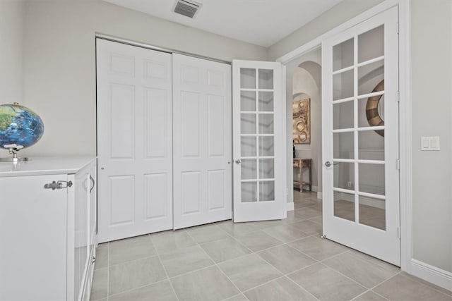 interior space with light tile patterned flooring, a closet, and french doors