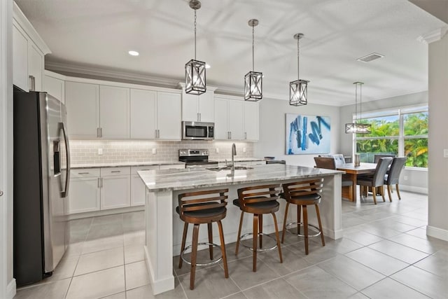 kitchen with white cabinetry, a center island with sink, pendant lighting, and appliances with stainless steel finishes