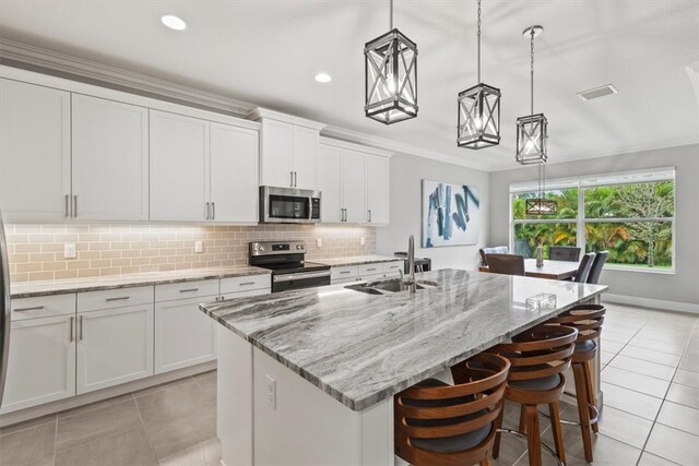 kitchen with hanging light fixtures, sink, a kitchen island with sink, and appliances with stainless steel finishes