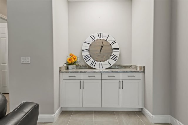 interior space featuring white cabinets, light tile patterned floors, and light stone counters